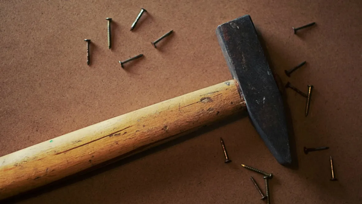 A hammer and nails on a wooden table top