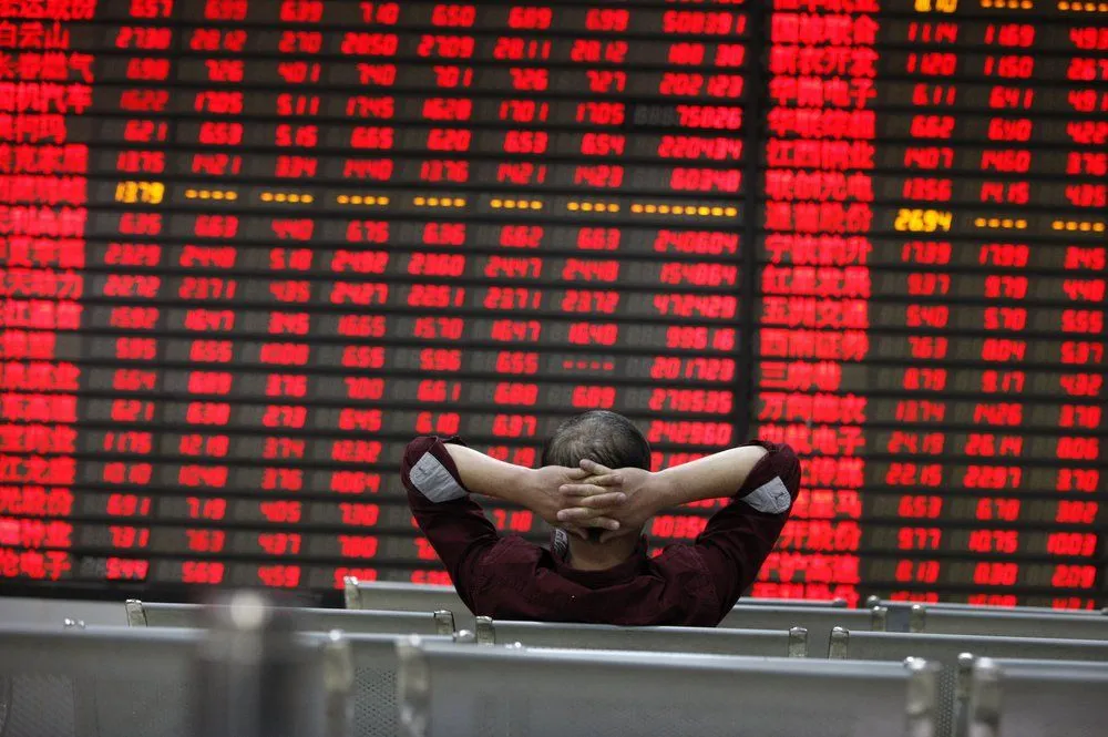 An investor sitting in front of a stock market board